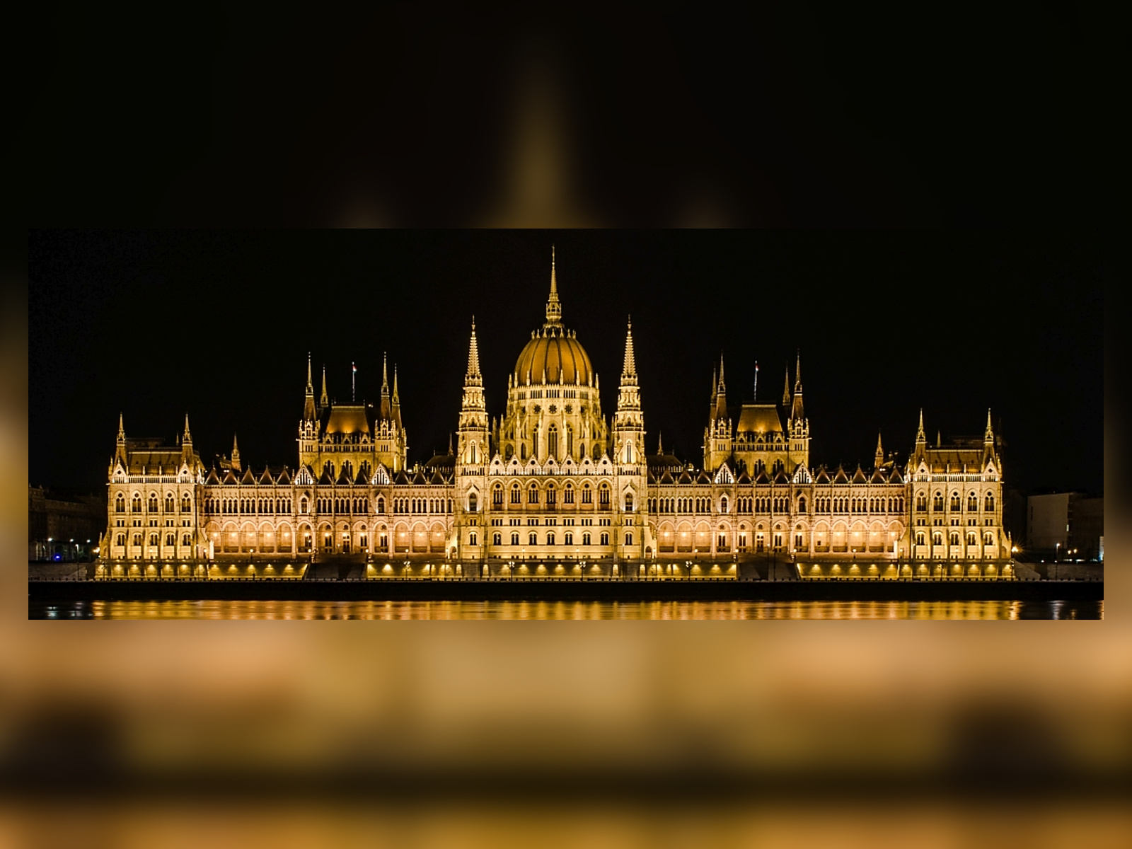 The Parliament lit up at night, seen across the Danube